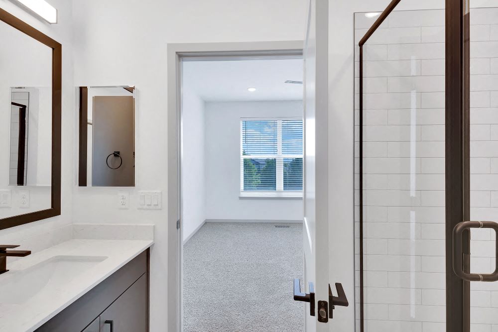 View from master bath with two sinks, vanity, glass shower doors and view of master bedroom